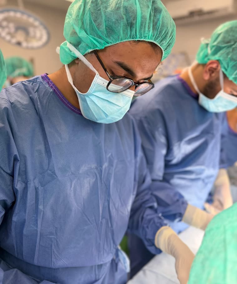 Aarham gowned and masked, assisting in an operating theatre